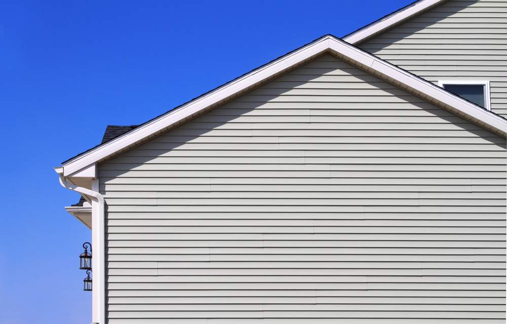 New home with gray vinyl siding and blue sky in the background