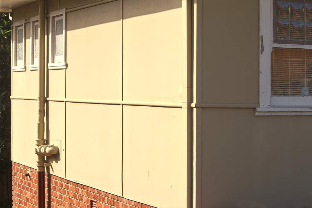 The side of an old asbestos cement house. Showing panel joins of the asbestos cement sheets. Asbestos cement is also known as fibro, fibrolite and fibrous cement. A source of airborne toxic fibres.