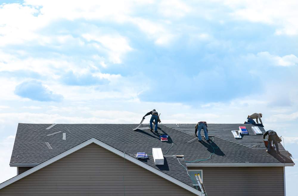 4 construction workers fixing roof against clouds blue sky, inst